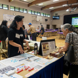 a woman in a black tshirt talking with a woman in black and white by books