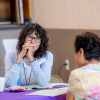 Nancy Okubo listening to a woman in floral shirt