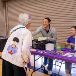 a woman in gray smiling to an older adult in white