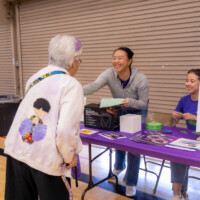 a woman in gray smiling to an older adult in white