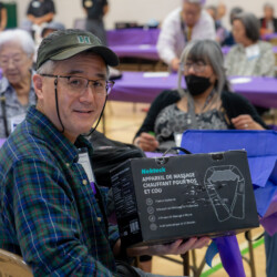 Man with a University of Hawaii visor holding a neck massager prize