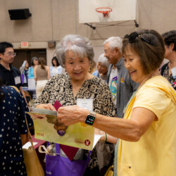 a woman in yellow and a woman in printed black shirt smiling at a camera