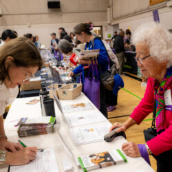 a woman in white writing down on a paper for a woman in pink