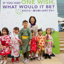 M PALMA PHOTO 2022 Smiling children and one woman in yukata posing in front of a sign at the summer festival