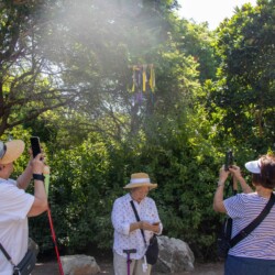 three women taking a photo of a wind chime