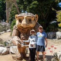 a man and a woman posing next to a wooden troll