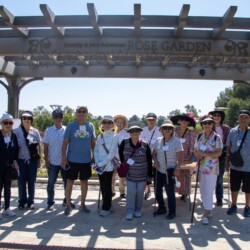 a group of people standing in front of the rose garden