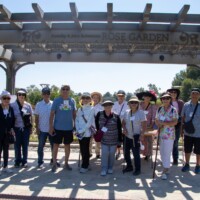 a group of people standing in front of the rose garden