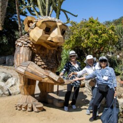 three women holding a troll's hand