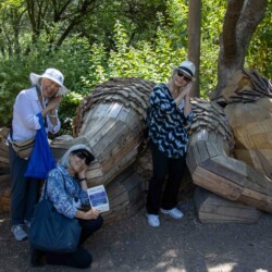 three women sleeping next to a wooden troll