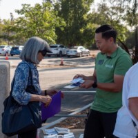 a man in a green shirt handing a woman in blue a nametag