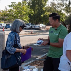 a man in a green shirt handing a woman in blue a nametag