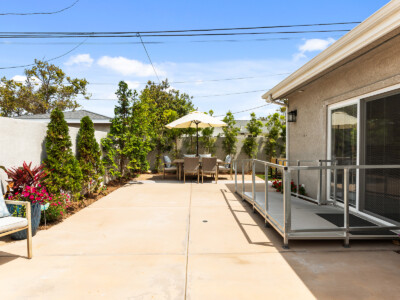 backyard with trees, ADA compliant ramp, and outdoor patio