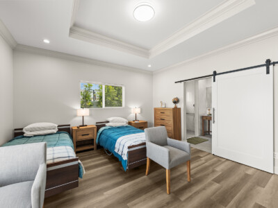two beds with blue comforter, two chairs, and a sliding door
