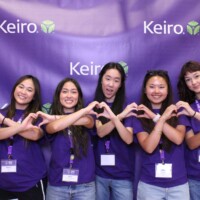 six volunteers posing at photo booth making hearts with hands