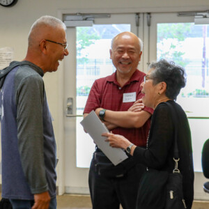 three people smiling and talking to each other