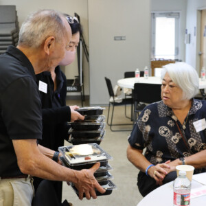 two people handing a woman a bento