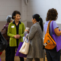 a woman in green talking with a woman in a black and white coat