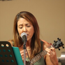woman singing while playing ukulele