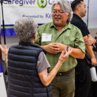 a man in green talking with a lady in a vest