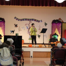 woman sining on stage with people watching