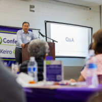 a man in a blue button down talking on a podium