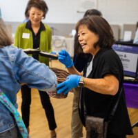 a woman in black taking tickets from a woman in blue