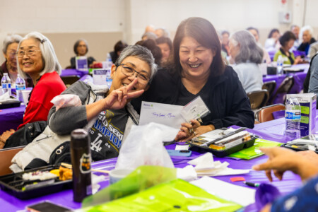a woman in a Dodger shirt and a woman in black holding on an envelope