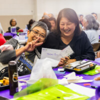 a woman in a Dodger shirt and a woman in black holding on an envelope
