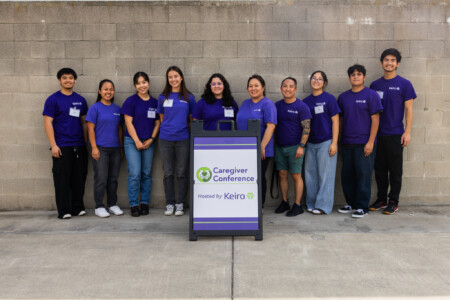 a group of volunteers in purple standing in front of the caregiver conference sign