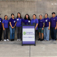 a group of volunteers in purple standing in front of the caregiver conference sign