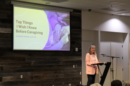 woman at podium with screen behind that says "Top Things I Wish I Knew Before Caregiving"