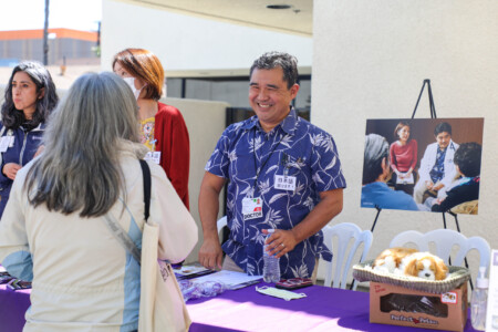 man smiling and talking at information table