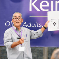 @2022_MPalmaPhotography Magician Bill Yamane holding up paper with a playing card drawn on it