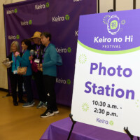 M PALMA PHOTO 2025 Photo Station sign with people taking a photo in the background