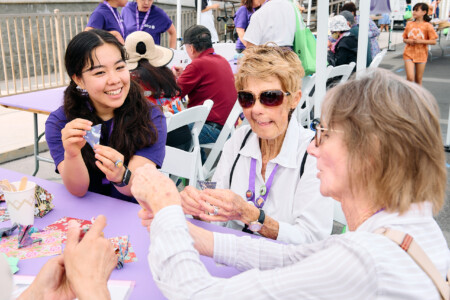 M PALMA PHOTO 2025 volunteer helping two attendees with origami