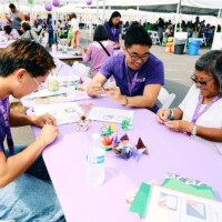 M PALMA PHOTO 2025 two volunteers helping women with origami