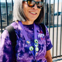 M PALMA PHOTO 2025 woman in purple tie dye shirt with 5 buttons on lanyard
