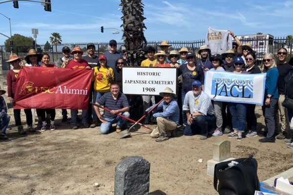 large group of people holding USC and Ventura County JACL banners at Historic Japanese Cemetery