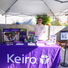 woman in beige tshirt behind a purple table