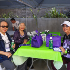two woman and one man sitting at green table