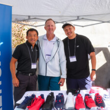 three men behind a white table with shoes