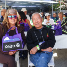 a man and woman smiling holding onto a purple bag