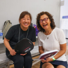 two woman smiling holding paddles