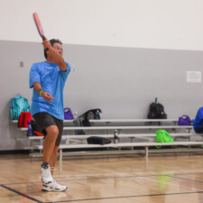 man in blue shirt hitting a ball