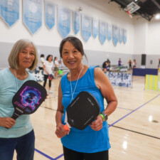 two woman posing with paddles and smiling