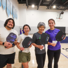 four people holding paddles and smiling