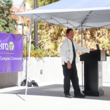 man in white talking by a podium
