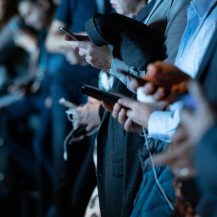 men with suits all looking on their smartphone
