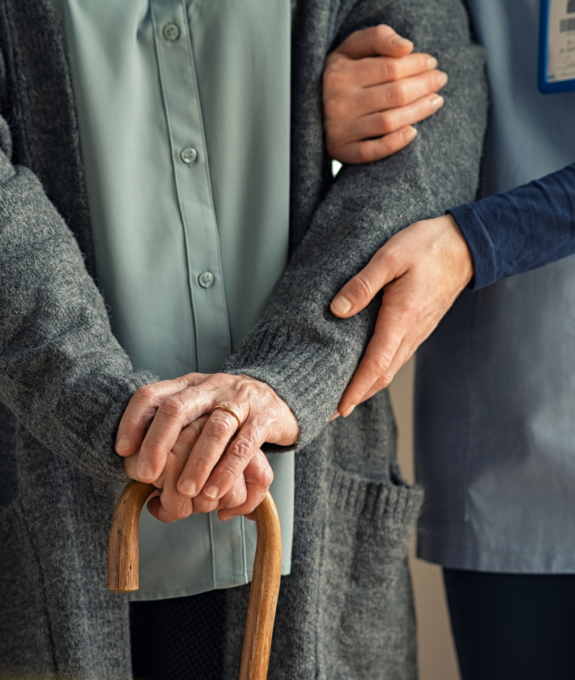 older adult with person holding them